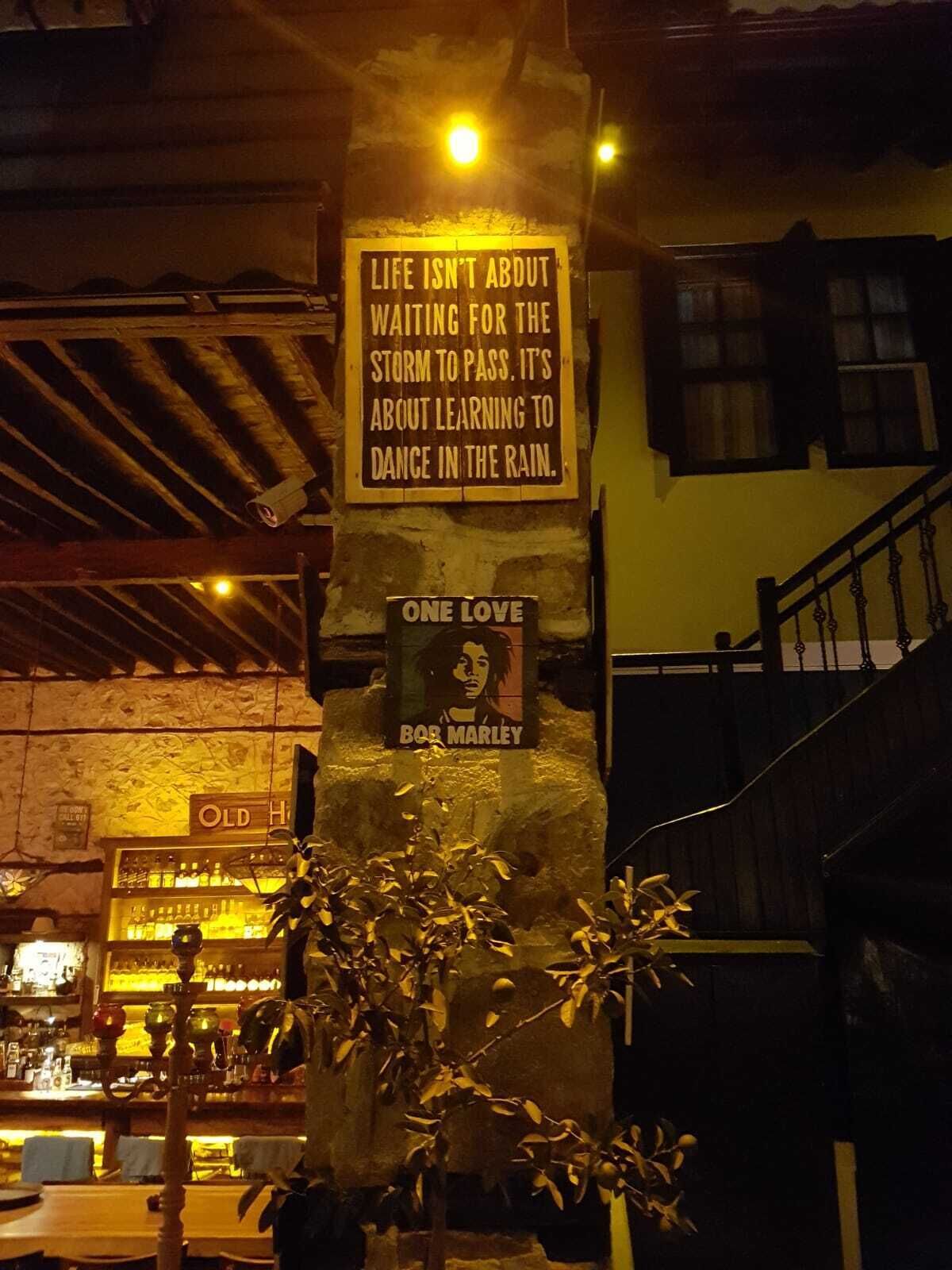 Une pancarte avec une citation sur la vie et le plaisir de danser sous la pluie, ainsi qu’une affiche de Bob Marley.
