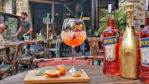 Une table avec des boissons, des bouteilles et une planche en bois sur laquelle sont disposées des tranches de fruits.