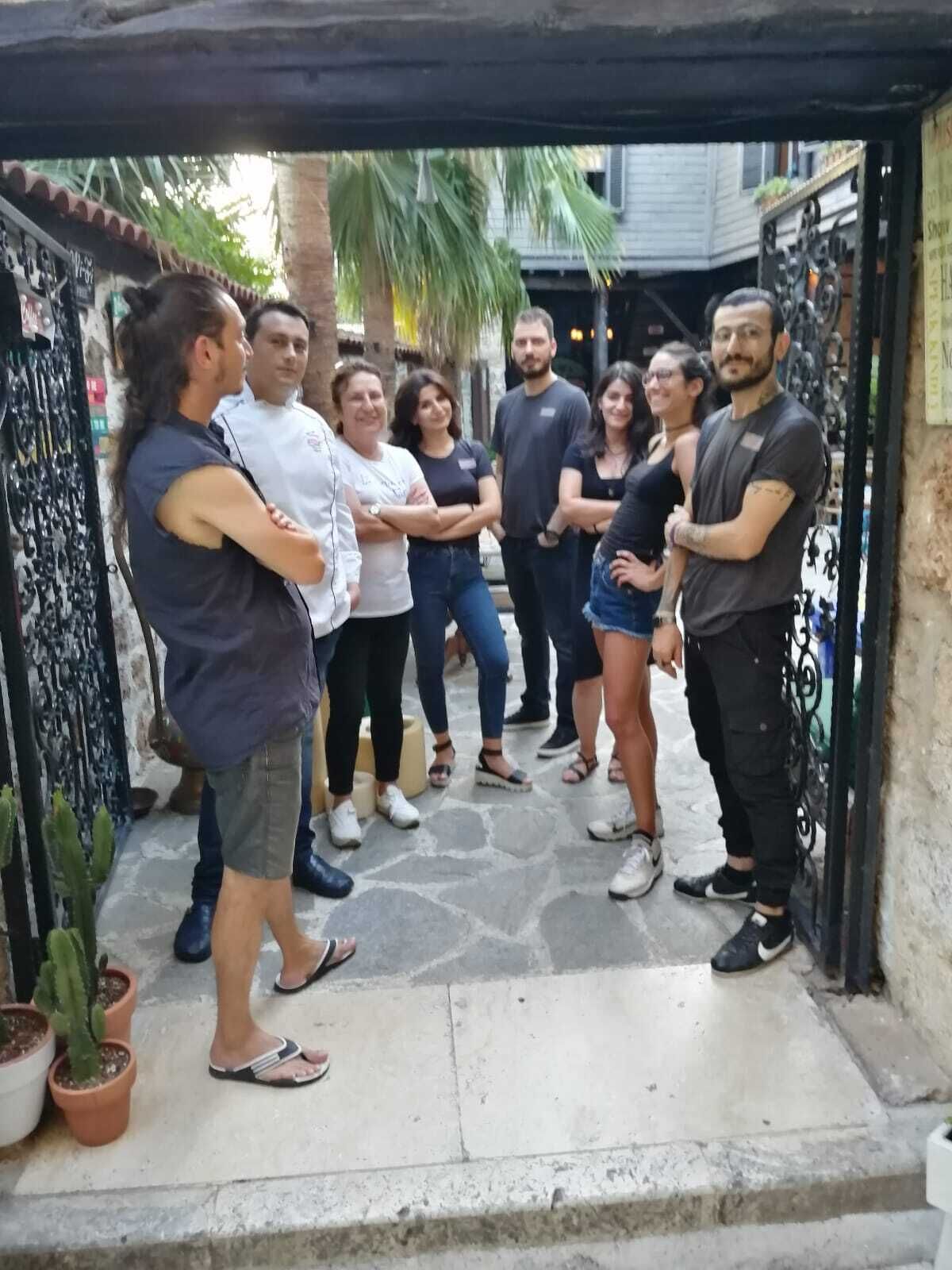 Un grupo de personas de pie en un patio con suelo de piedra y macetas con plantas.