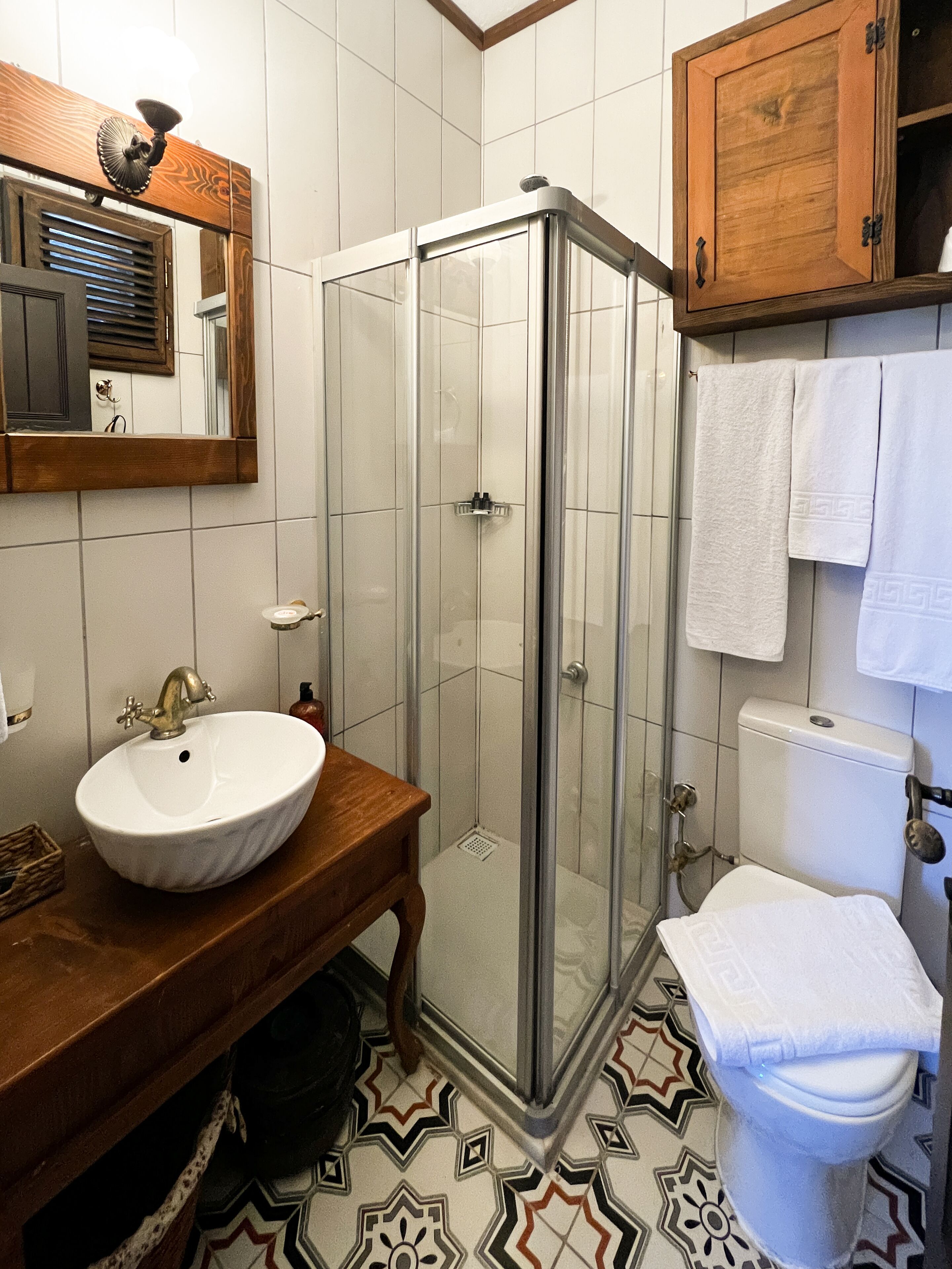 A bathroom with a glass-enclosed shower, a white sink, and a wooden vanity.