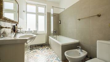 A bathroom with a bathtub, a sink, a bidet, and a toilet.