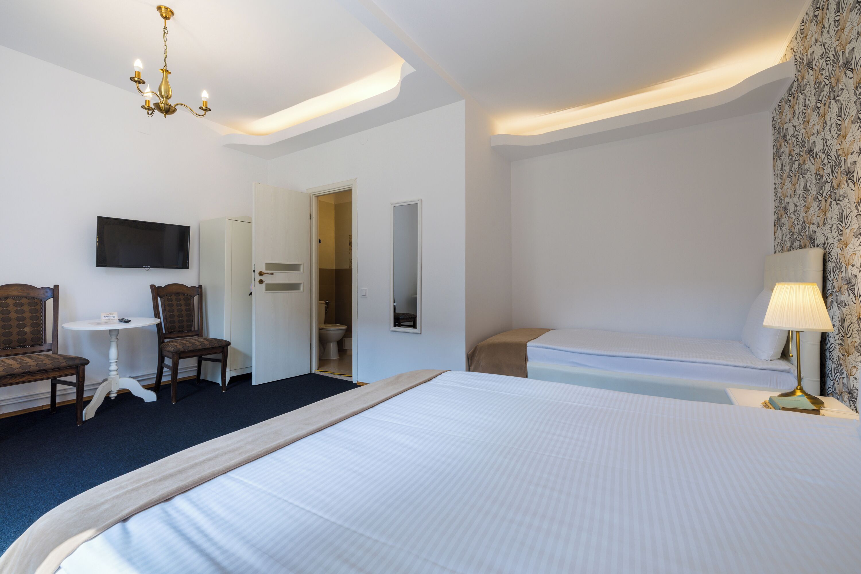 A hotel room with a large bed, a television, a desk, and a chair.
