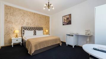A hotel room with a large bed, two bedside tables with lamps, a desk with a chair, and a painting on the wall.