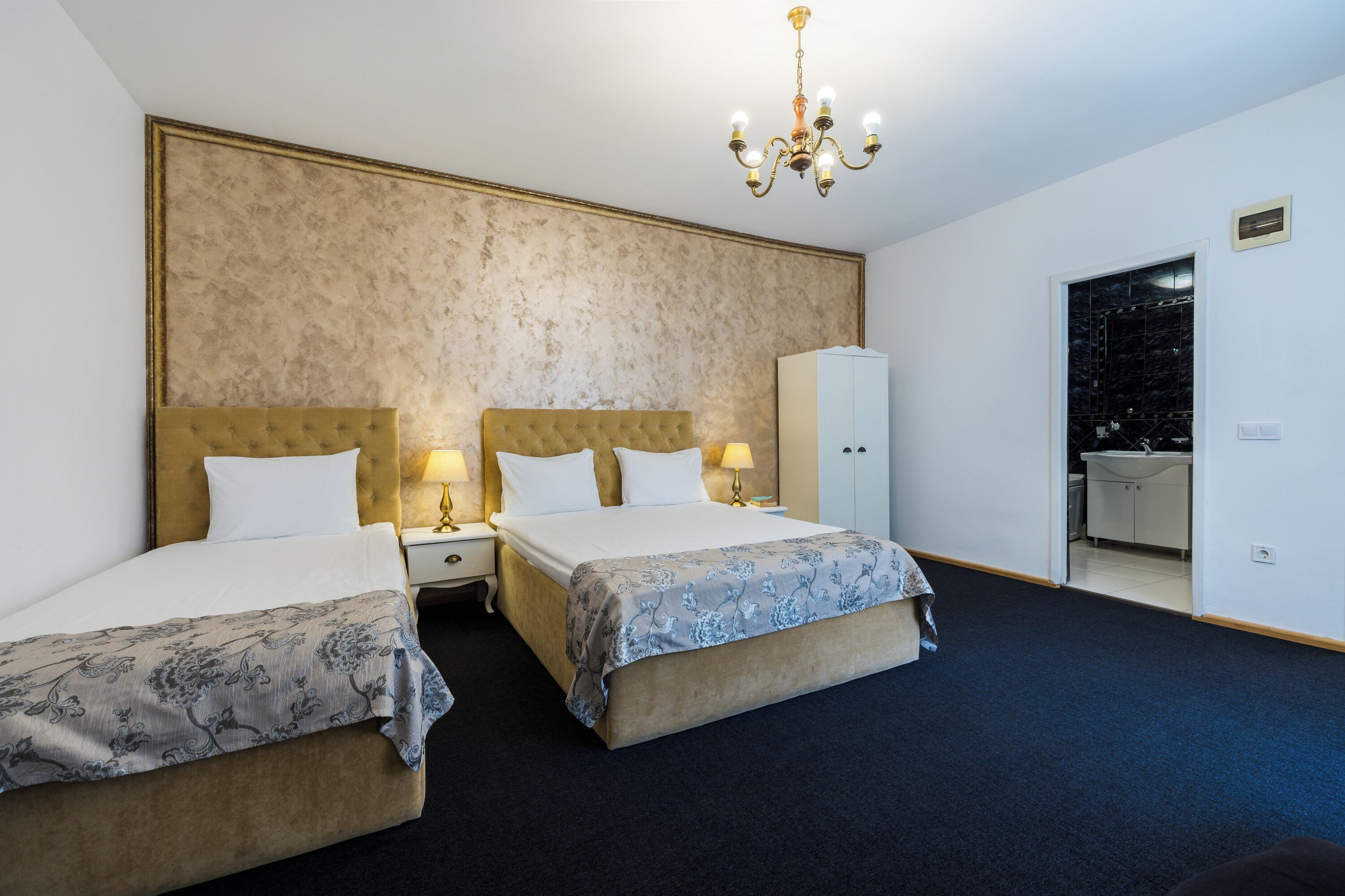 Une chambre d’hôtel avec deux lits, un lustre, une armoire et une vue sur la salle de bain.