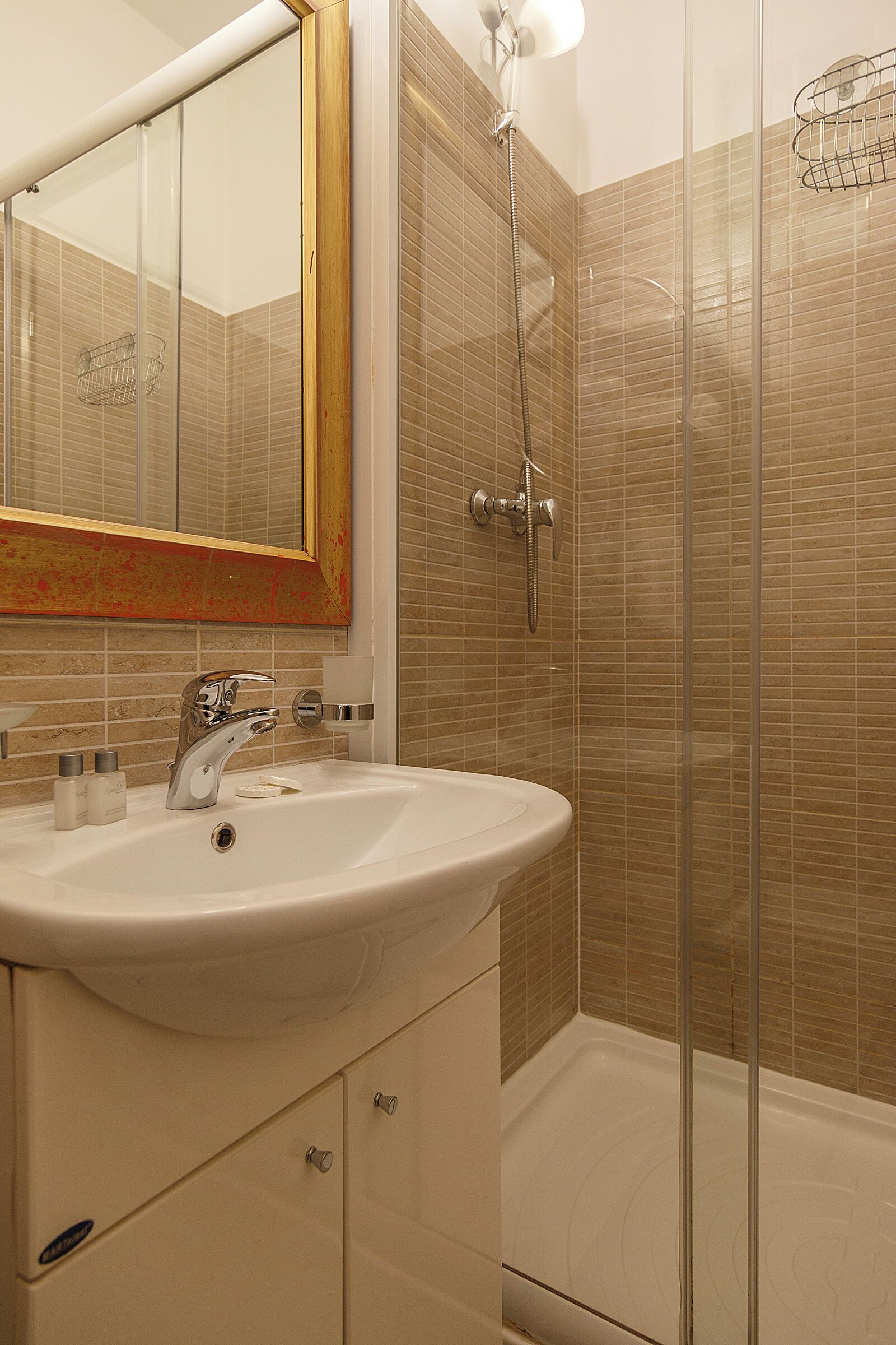 A bathroom with a sink, mirror, and shower.