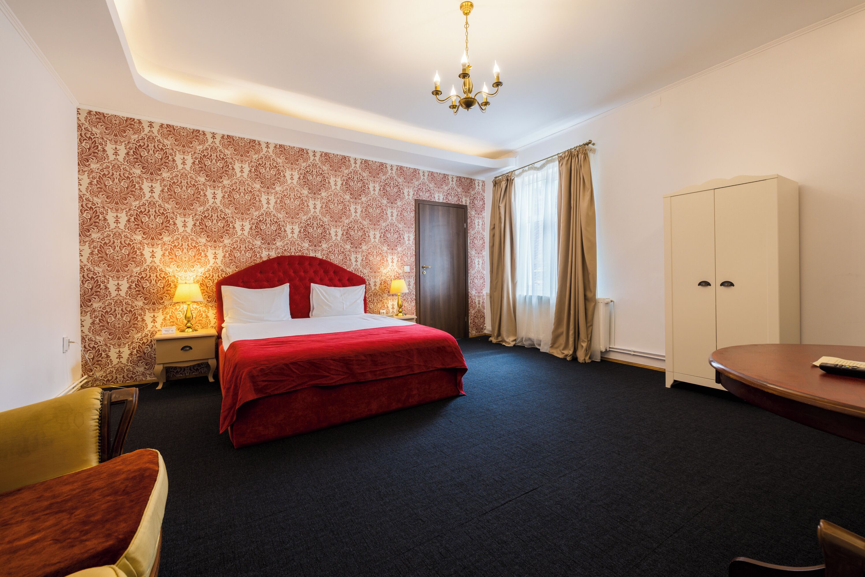 Una habitación de hotel con una cama grande, un armario, un escritorio y una silla.