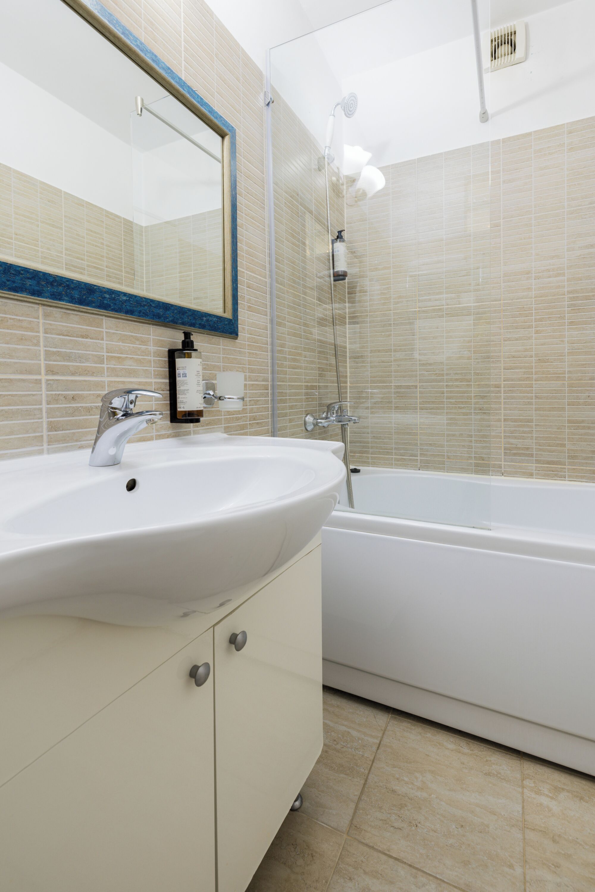 A bathroom with a white sink, mirror, and bathtub.
