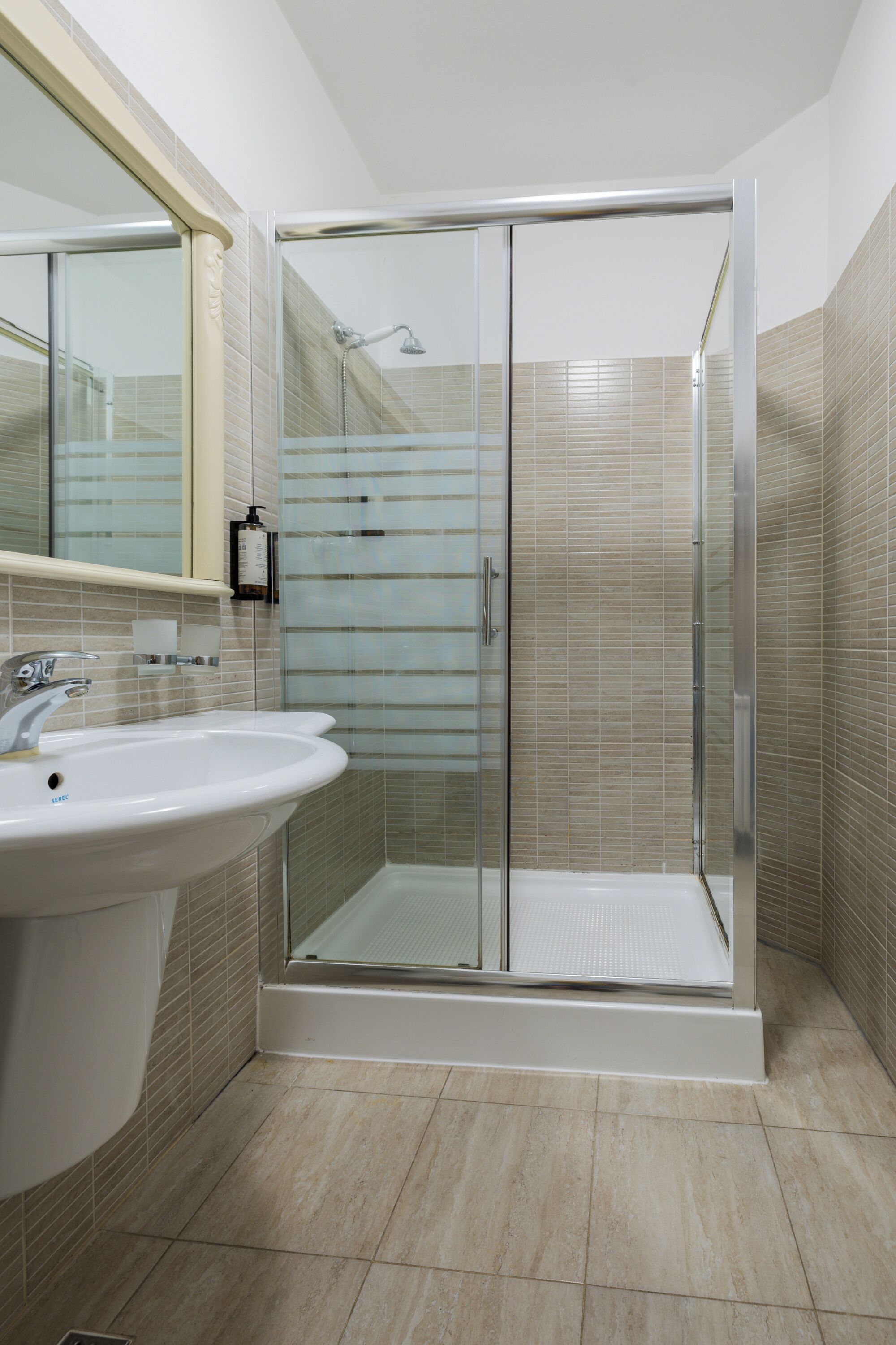 A bathroom with a glass-enclosed shower, a sink, and a mirror.