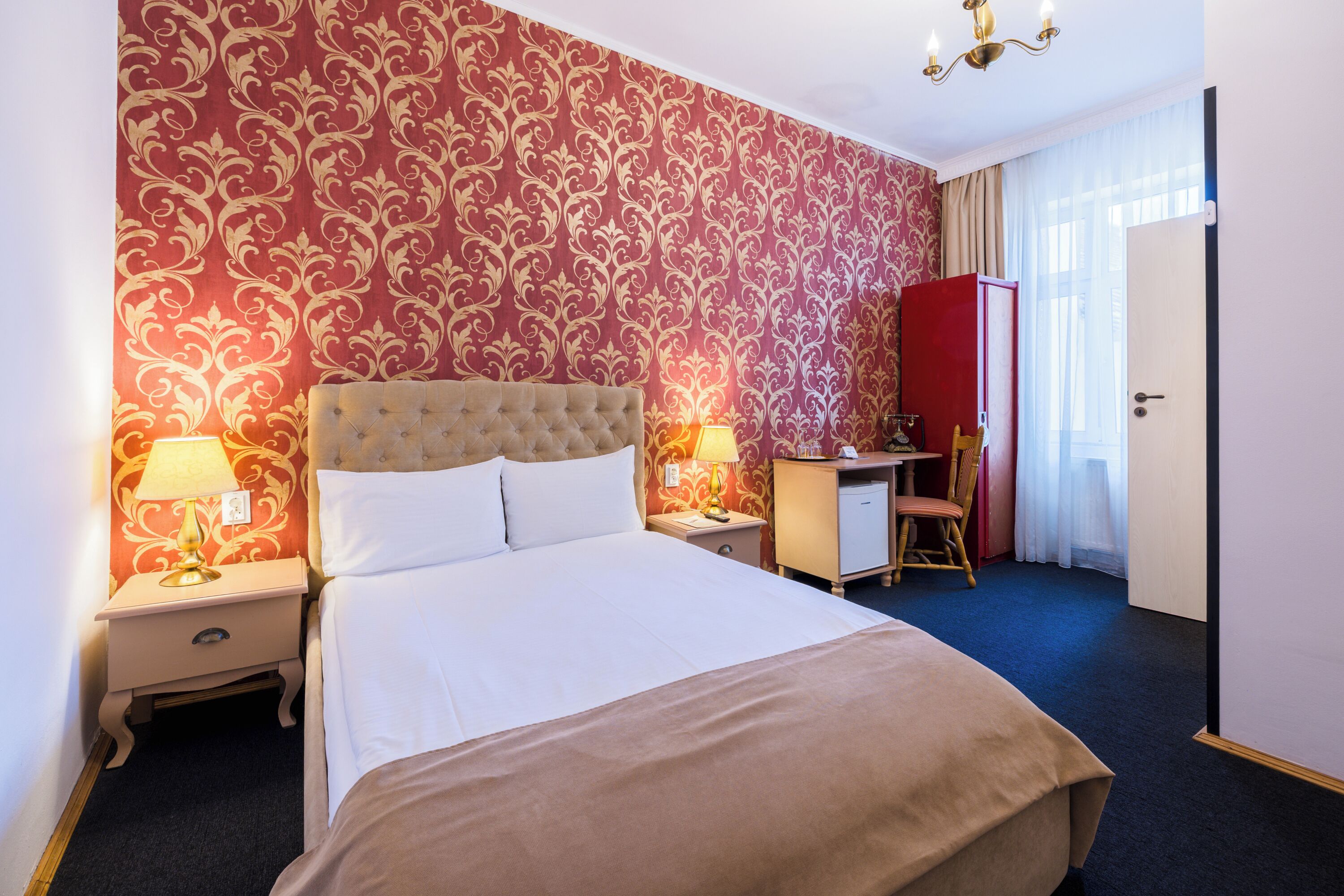 Een hotelkamer met een groot bed, twee nachtkastjes met lampen, een bureau, een stoel en een garderobe.