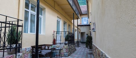 Un patio con suelo de baldosas, mobiliario exterior y un edificio con balcón.
