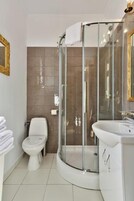 Un baño moderno con ducha de vidrio, inodoro y lavamanos con espejo.