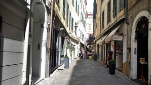A narrow street with shops and cafes, stone pavement, and potted plants. - Relais Virginia Home (Sanremo)