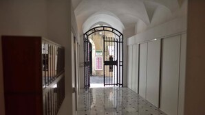 A hallway with a tiled floor, a metal gate, and a view of a building in the distance. - Relais Virginia Home (Sanremo)