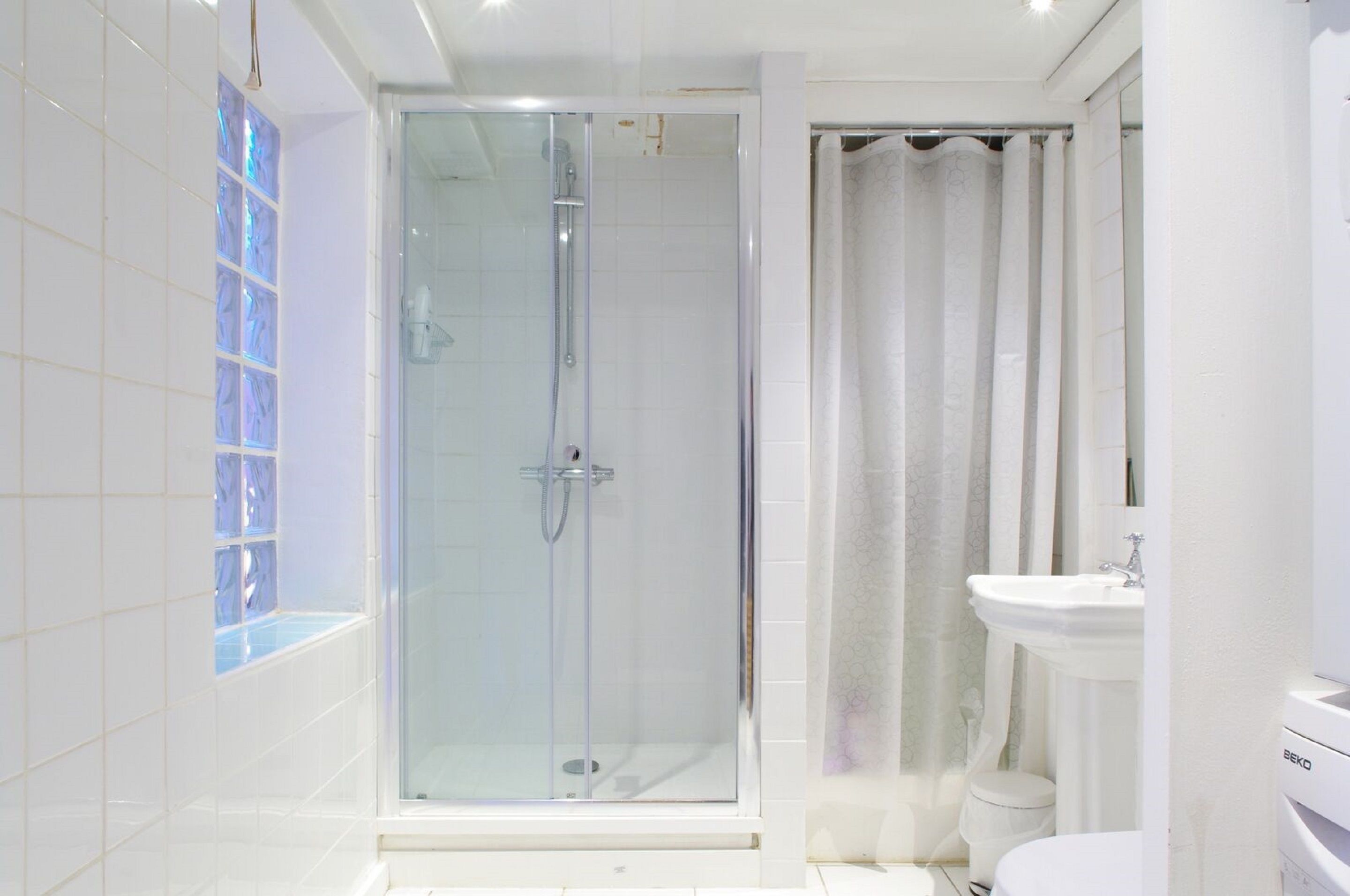 Uma casa de banho moderna com cabine de duche em vidro, lavatório branco e sanita.