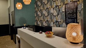 A reception desk with a menu board, a laptop, and a decorative lamp. - Hotel Actuel Chambéry Centre (Chambery)