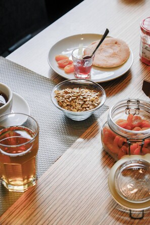 A table with a plate of food, a bowl of oats, a jar of dried fruit, and a glass of tea.