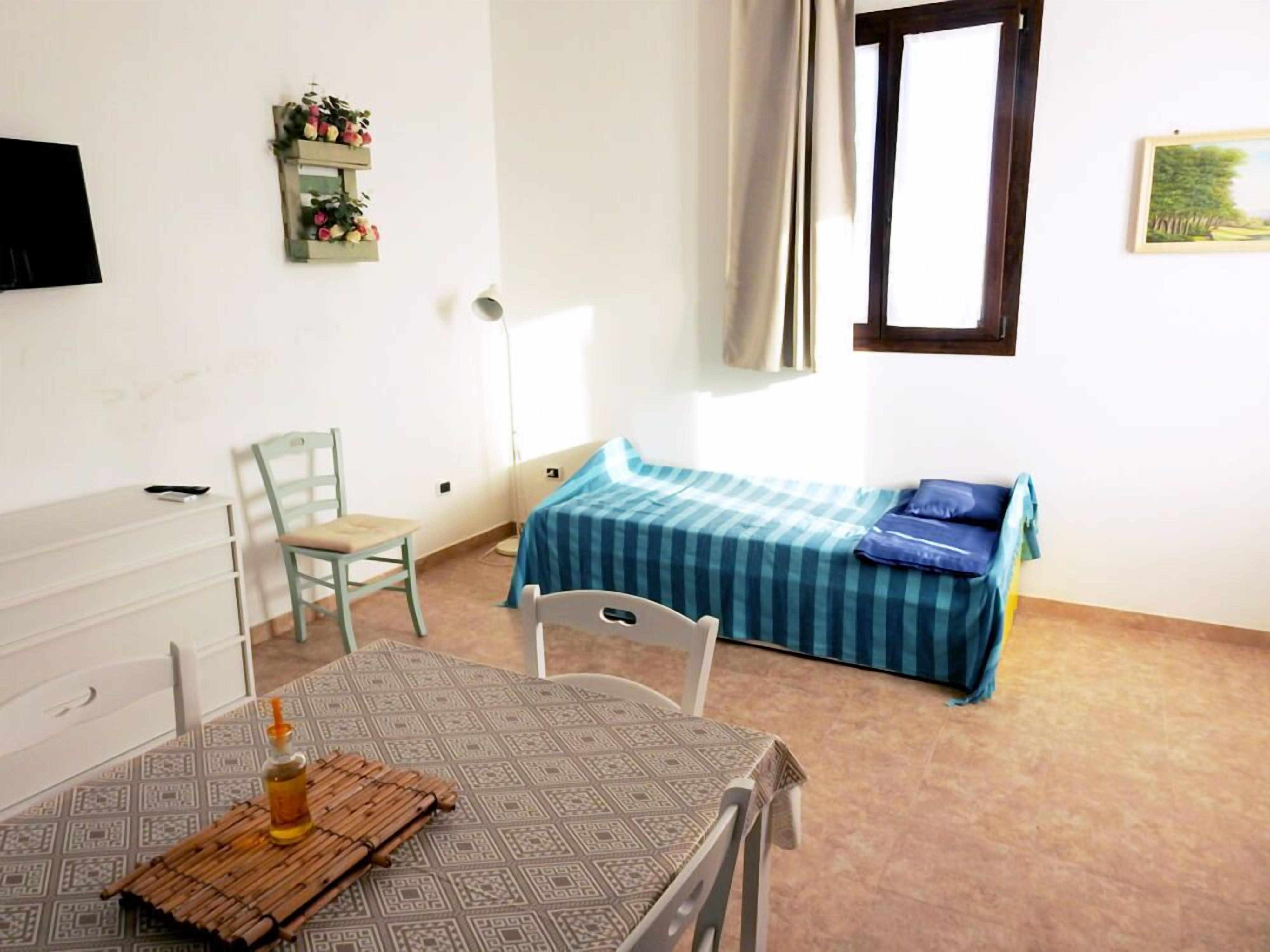 Une chambre comprenant un lit, un bureau, une chaise et une table avec un tapis et une bouteille.