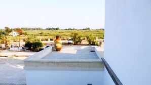 A white building with a flat roof, a potted plant, and a large vase. - Masseria Prisuti (Manduria)