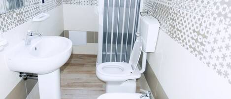 A bathroom with two sinks, a toilet, and a shower enclosure.
