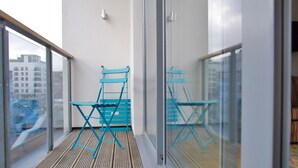 A balcony with a wooden floor, two blue folding chairs, and a glass railing. - The London Agent Clerkenwell Super Nice (London)
