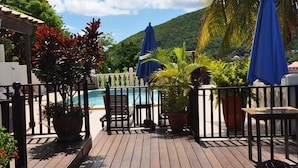 A wooden deck with a pool, potted plants, and blue umbrellas. - Rodney Bay Suites (Gros Islet)