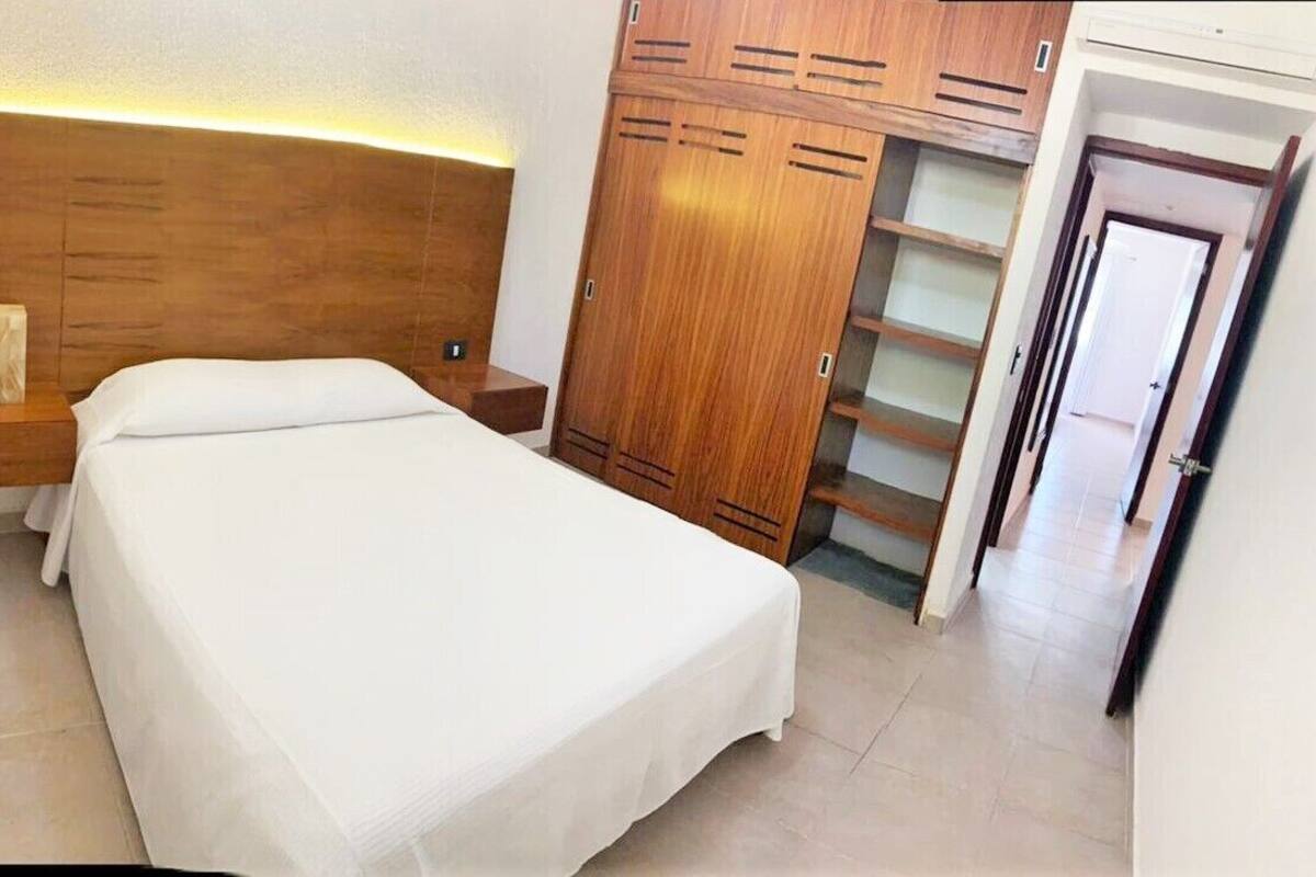 A bedroom with a bed, wooden wardrobe, and a nightstand.