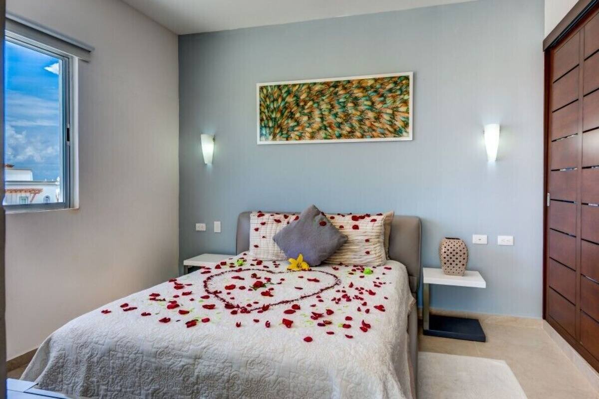 A bedroom with a bed, a wall-mounted artwork, a nightstand, and a wardrobe.