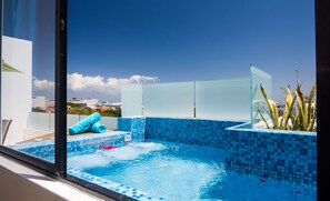 A rooftop pool with blue mosaic tiles, a glass partition, and a view of the cityscape. - Carmen Sol Rentals Apartamentos (Playa del Carmen)