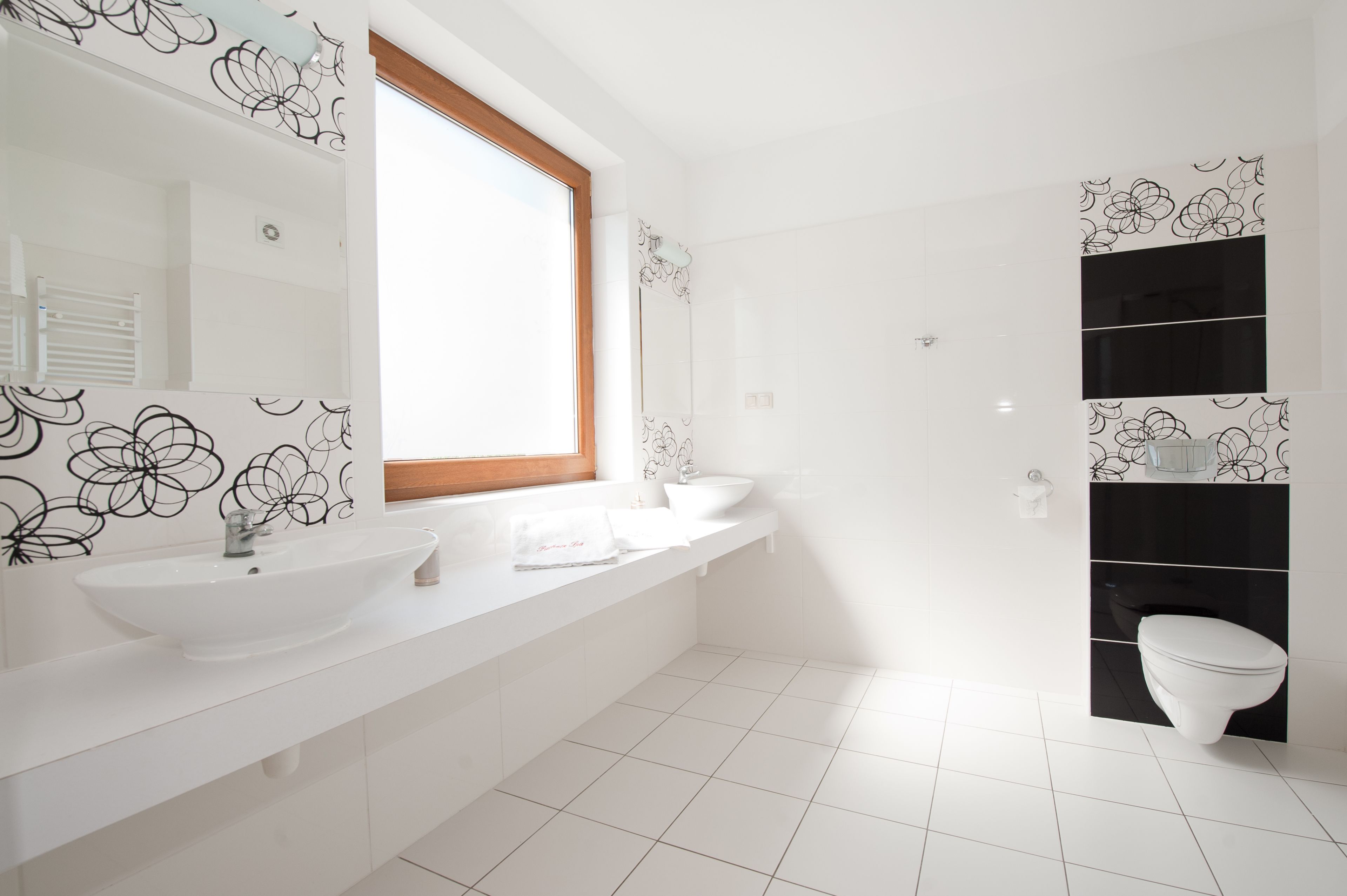 A modern bathroom with two sinks, a toilet, and a shower.