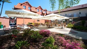 Eine Terrassenanlage im Freien mit Tischen und Stühlen, umgeben von einem Garten mit rosa Blüten.