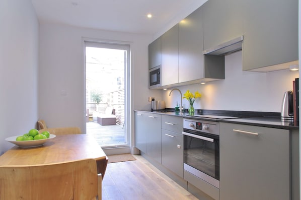 A modern kitchen with grey cabinets, a built-in microwave, and a stainless steel oven.