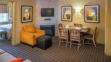 Una habitación de hotel con chimenea, un televisor montado en la pared y una zona de comedor con sillas y una mesa.