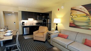 Quarto de hotel compacto com cozinha compacta, área de refeições e sala de estar.