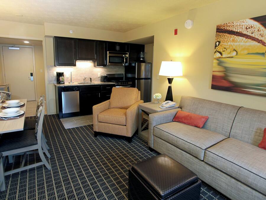 A compact hotel room with a kitchenette, a dining area, and a living space.