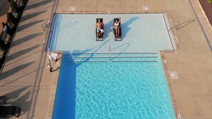 An aerial view of a rectangular swimming pool with two lounge chairs on opposite sides.