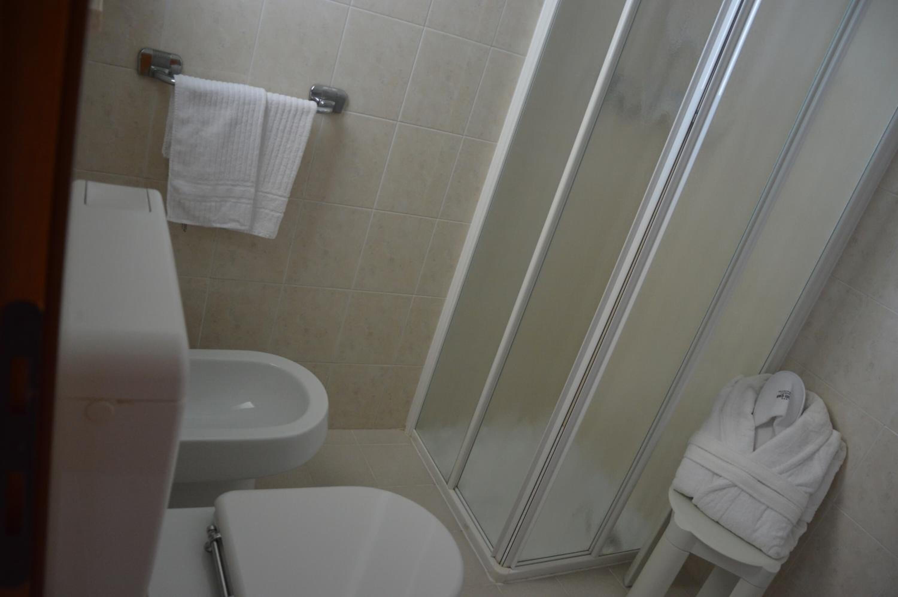 Ein Badezimmer mit Toilette, Bidet und einer Duschkabine aus Glas.