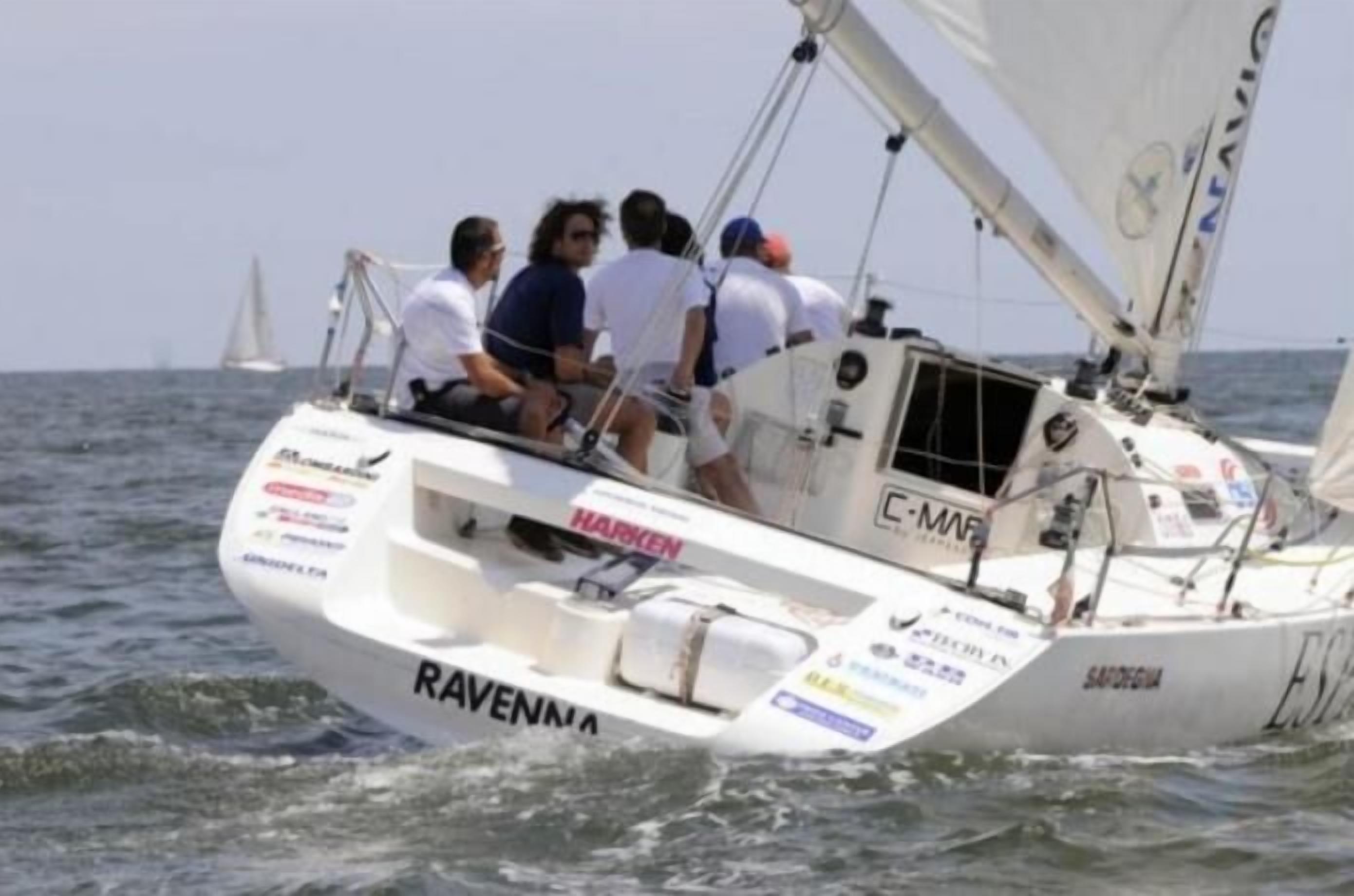 Un voilier portant le nom « RAVENNA » sur sa coque, naviguant sur l’eau.