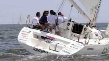 Un voilier portant le nom « RAVENNA » sur sa coque, naviguant sur l’eau.