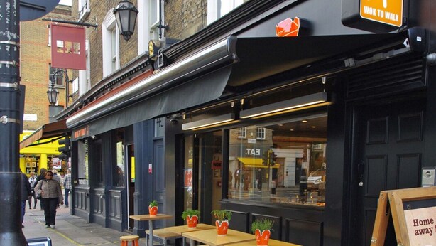 A street-side café with outdoor seating and a sign indicating a 'Wok to Walk' service. - The London Agent Fitzrovia Studio 1 (London)