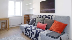 A modern living room with a sofa, a painting, and a window. - The London Agent Fitzrovia Studio 2 (London)