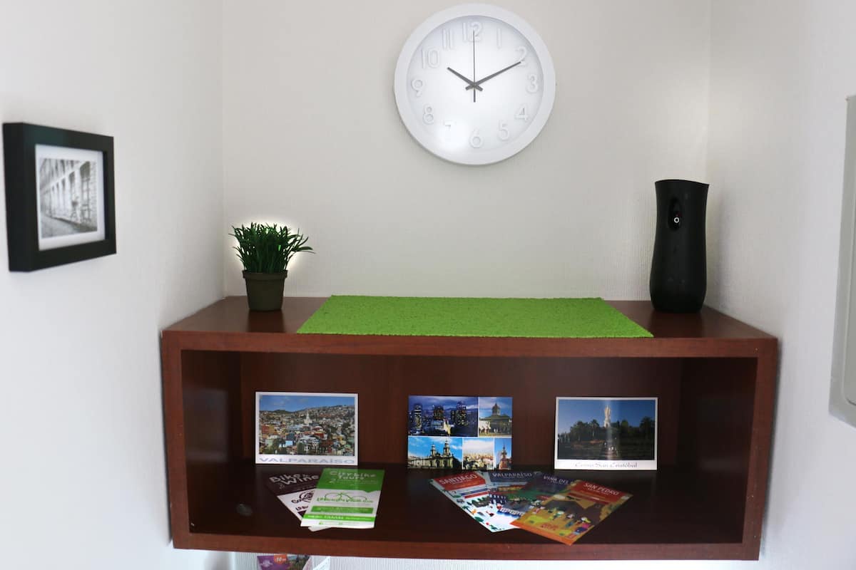 A wooden reception desk with a clock, framed picture, potted plant, and travel brochures.