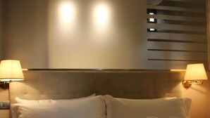 A hotel room with a bed, two bedside lamps, a headboard, and a towel art display. - Verona4rent Roberto (Verona)