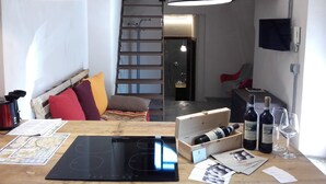 A cozy room with a wooden table, a black induction cooktop, a wooden wine box, and wine bottles. - Verona4rent Roberto (Verona)