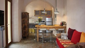 A compact kitchen with a wooden table and bar stools, a refrigerator, and a microwave. - Verona4rent Roberto (Verona)
