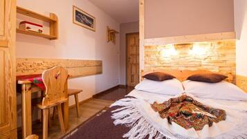 A bedroom with a wooden headboard, a bed with white linens, a colorful throw blanket, and a wooden chair.