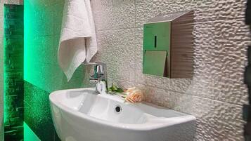 Un baño con un lavamanos blanco, iluminación verde y una pared con textura.