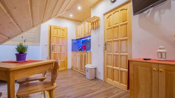 A wooden kitchen with a dining area, wooden cabinets, and a small trash bin.