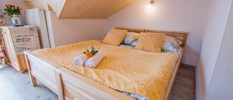 Una cama de madera con cabecera, una mesita de noche con lámpara y una pequeña planta en el buró.