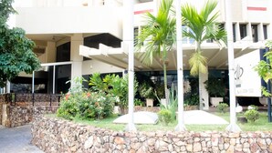 Un hotel con un muro in pietra, palme e diverse piante.