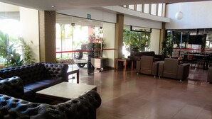 Un'ampia hall con divani in pelle, un tavolino da caffè e un'area pranzo con sedie e una TV.